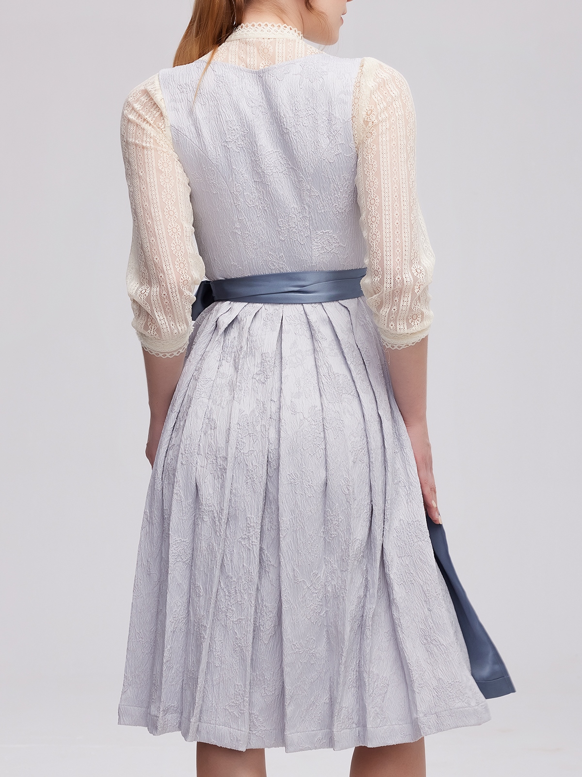 Ein elegantes beige Dirndl mit blauer Schürze – perfekt für festliche Anlässe.